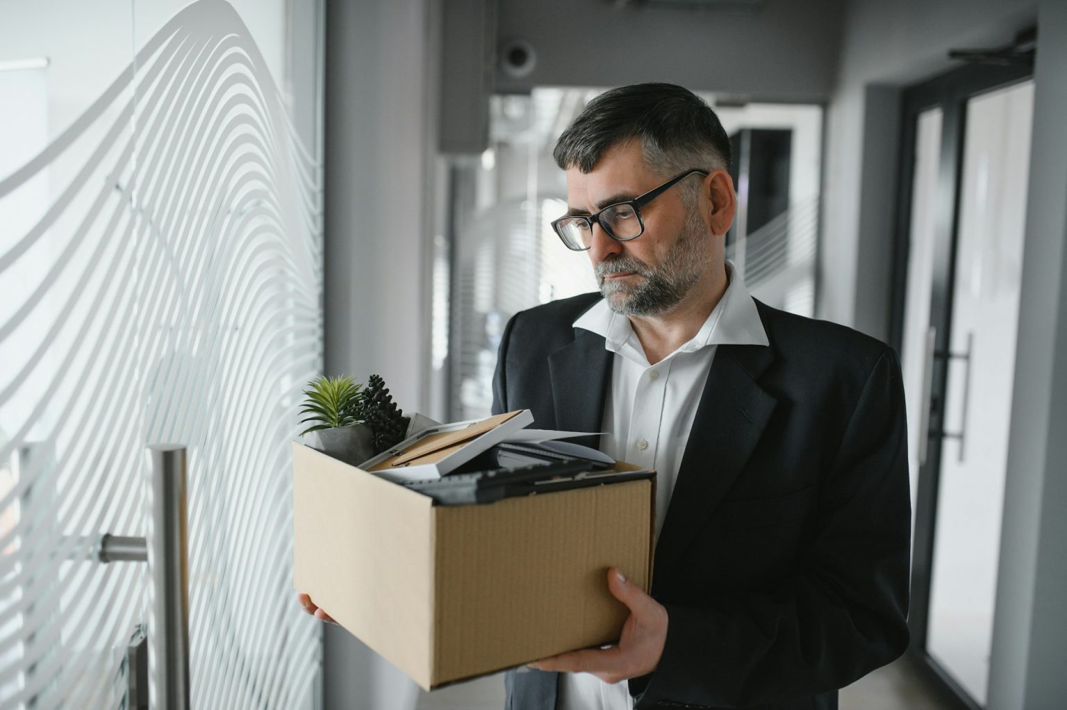 Portrait of sad dismissed senior old business man worker taking his office supplies in the box