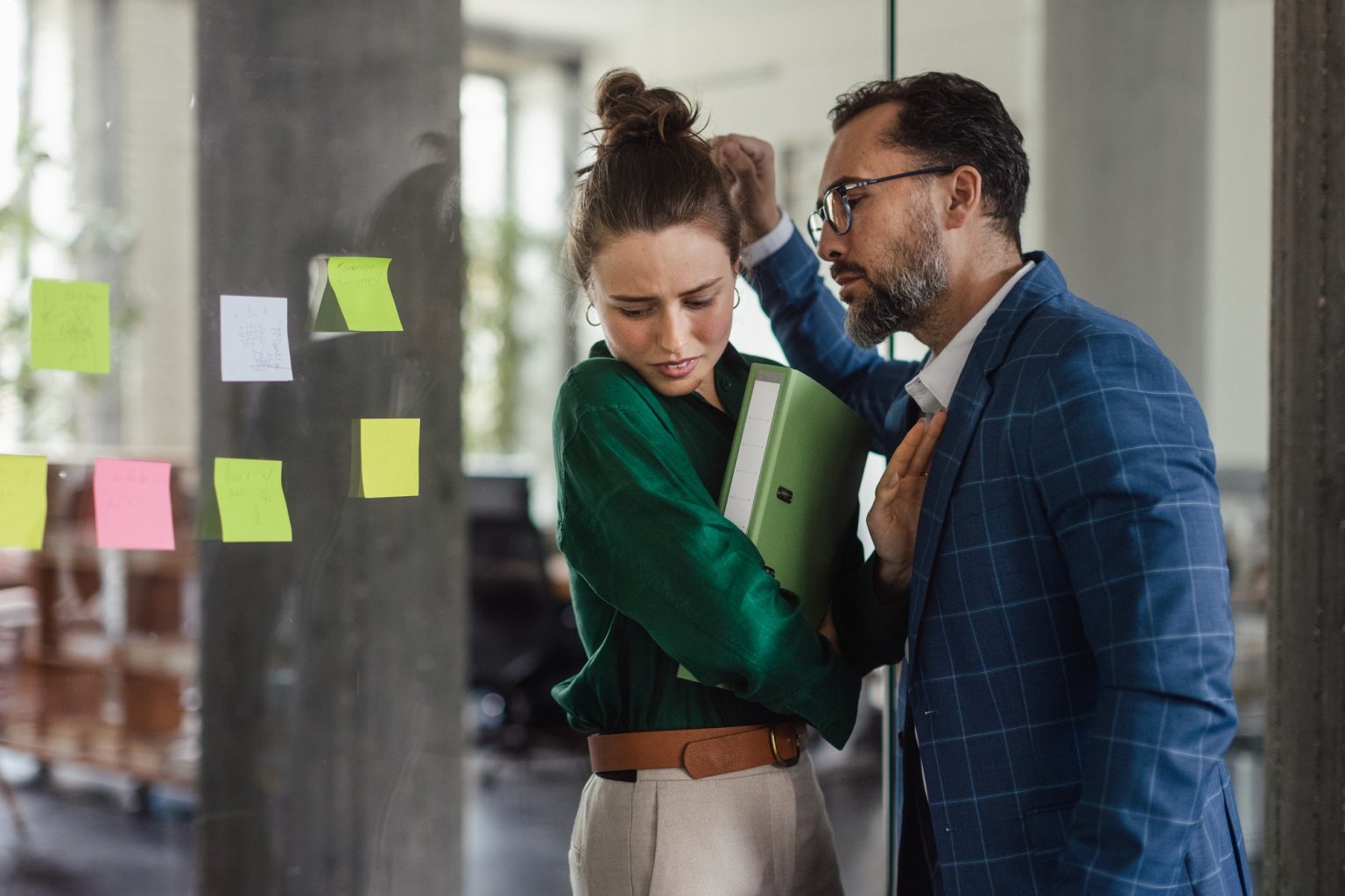 Mature man abusing his younger colleague, concept of harassment at workplace.